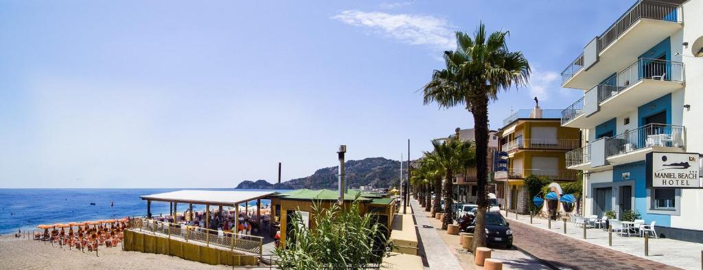 a street next to the ocean with a beach and buildings at Maniel Beach Hotel in Letojanni