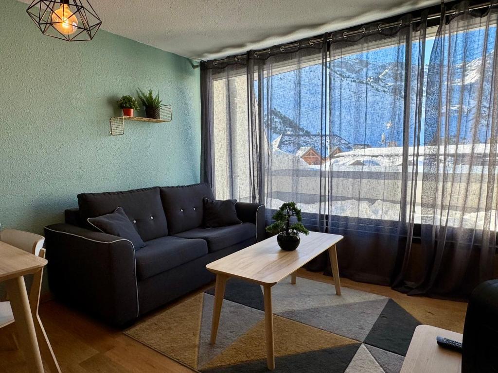 a living room with a couch and a large window at Plein centre station vue imprenable in La Mongie
