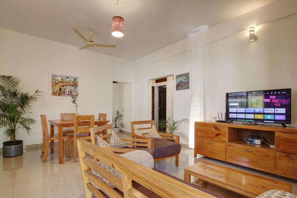 a living room with a television and a dining room at Genesis Abode - Cosy 2 BHK Bungalow in Assagao in Mapusa