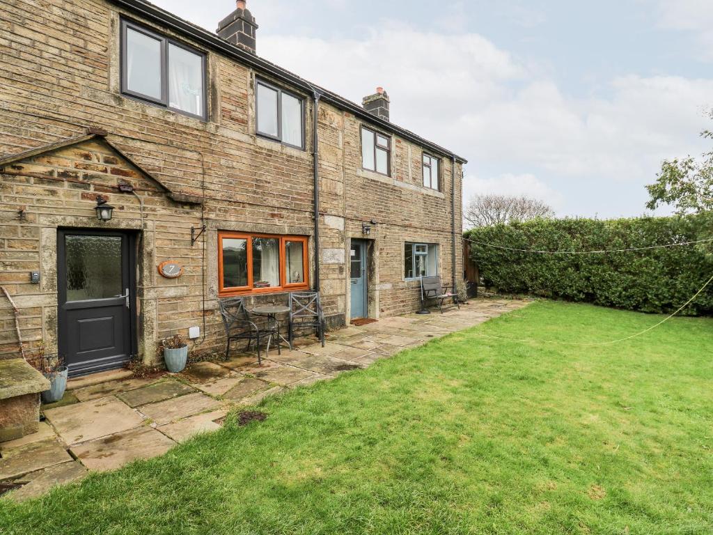 an exterior view of a brick house with a yard at Boshaw Cottage in Holmfirth