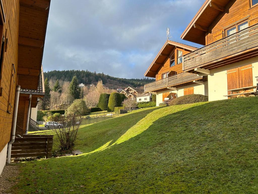 une maison avec une colline herbeuse à côté d'une maison dans l'établissement Joli Duplex sur la rive du lac, à Gérardmer