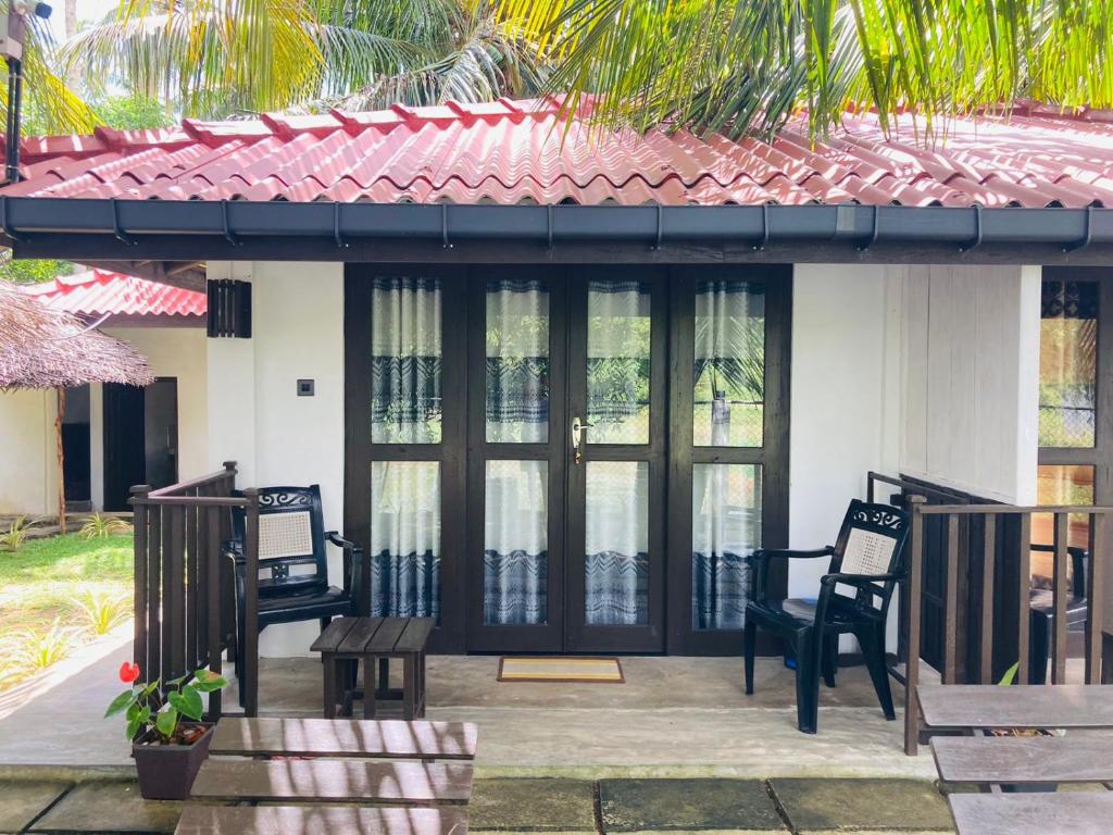 Casa con porche con sillas y ventanas en kingfish villa and restaurant, en Ranna
