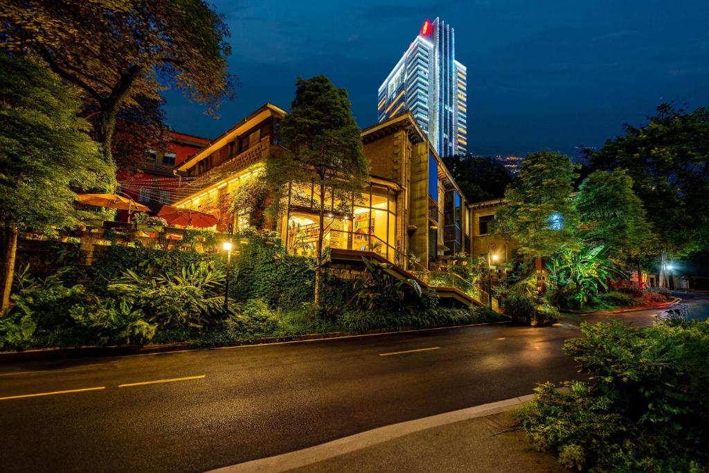 a building on the side of a street at night at Wuyu Hotel - Chongqing Shapingba Three Gorges Plaza in Chongqing