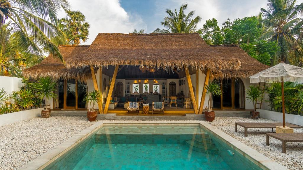 a villa with a swimming pool in front of a house at Bundi's Villa in Gili Air