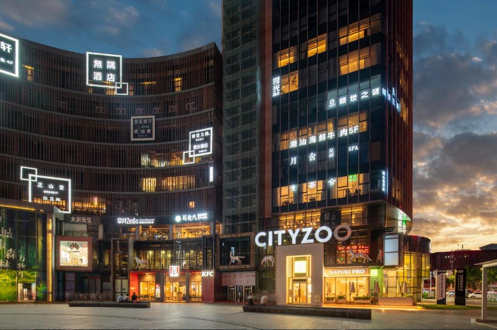 een groep van hoge gebouwen in een stad 's nachts bij Xunguang Hotel - Chongqing Liangjiang Happiness Plaza in Chongqing
