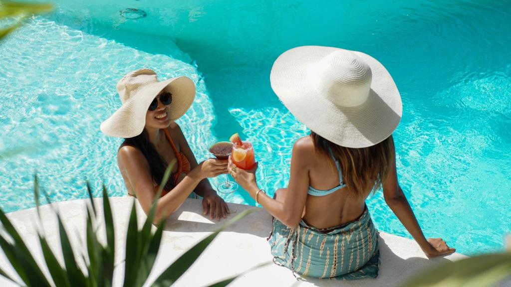 dos mujeres jóvenes con sombreros comiendo helado junto a una piscina en Happiness Boutique Resort, en El Nido