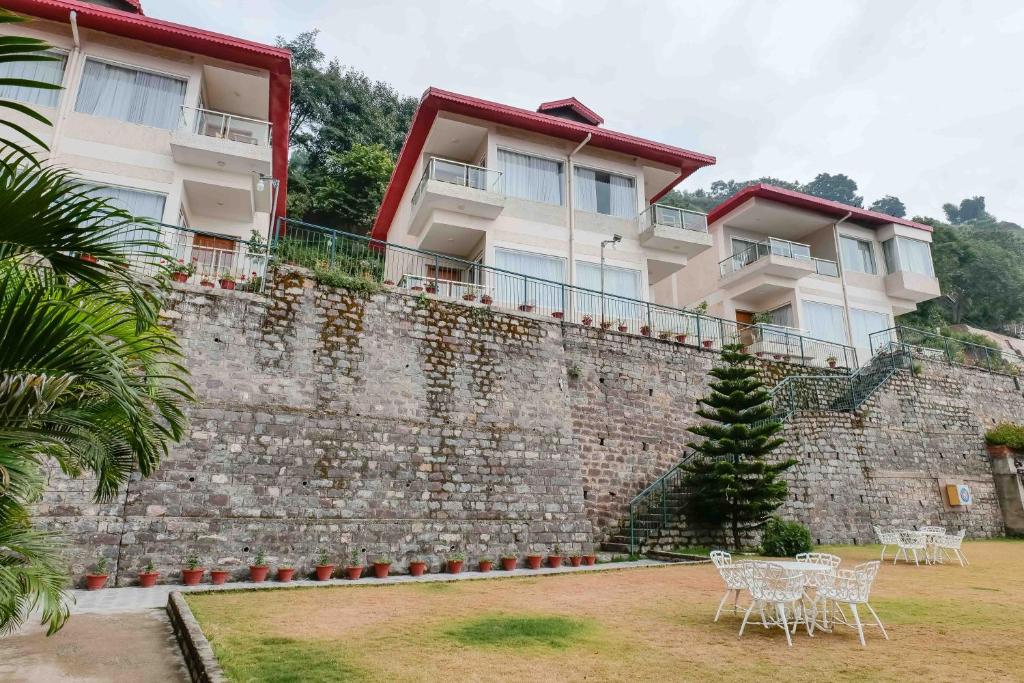 a brick wall with tables and chairs in front of a building at The Fern Surya Resort Kasauli Hills, Dharampur in Kasauli