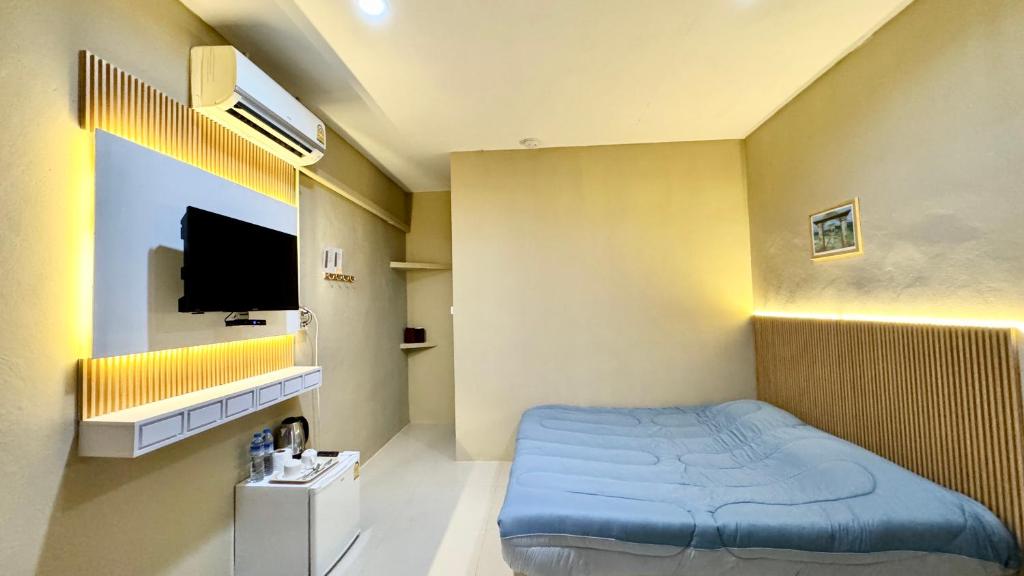 1 dormitorio con 1 cama azul y TV en มาชิลล์ รีสอร์ท สังขละบุรี en Sangkhla Buri