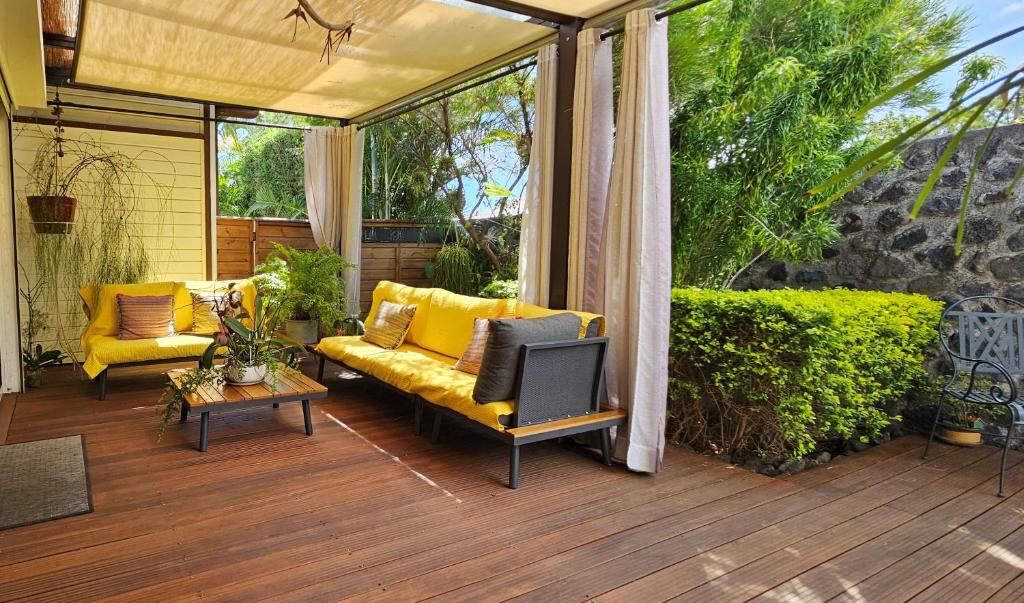 a patio with a yellow couch on a wooden deck at Villa YSANGA in Saint-Pierre