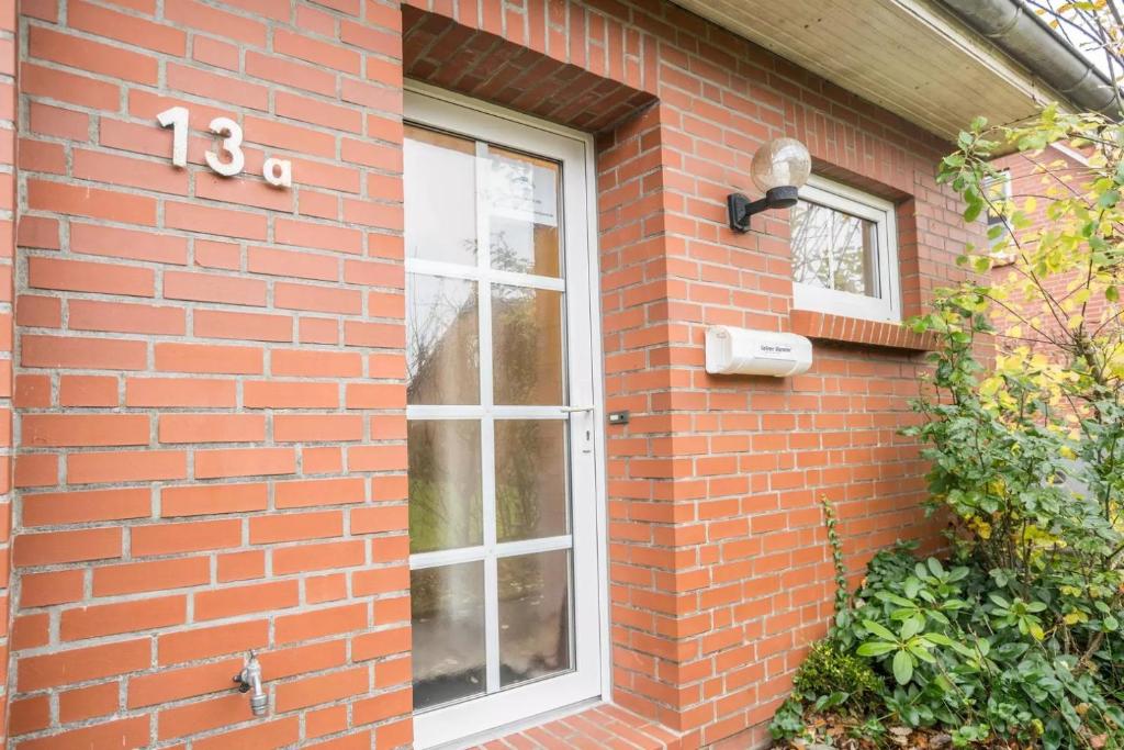 a brick building with a door and a window at Das Haus Konstantin heißt Sie und Ihre(n) Vierbeiner herzlich willkommen. in Neßmersiel