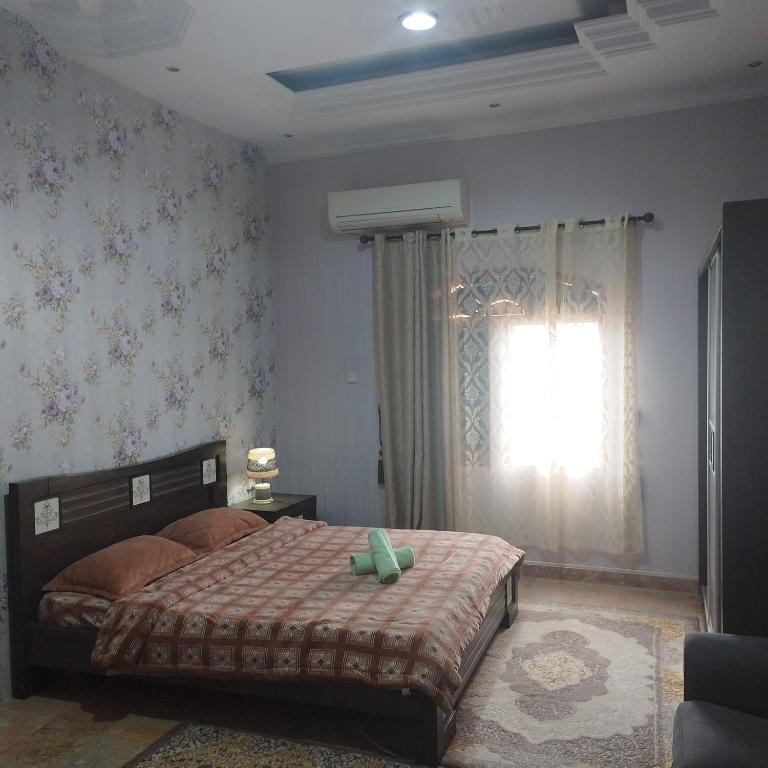 Un dormitorio con una cama grande y una ventana en العين الهيلي مصباح بيت 10, en Al Ain