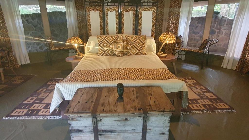 Double Tent - Dolly Farm & River Camp في Usa River: غرفة نوم بسرير وشنطة خشبية