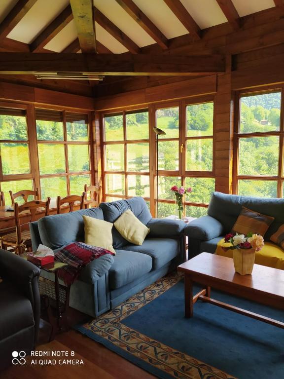 a living room with a blue couch and windows at CASA TABLADO HELENA in Belmonte de Miranda
