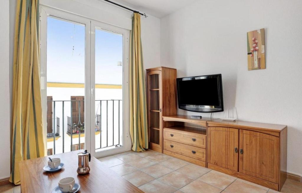 een woonkamer met een televisie en een balkon bij Apartamento Pérez Zara 6 in Conil de la Frontera