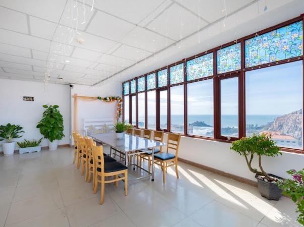 a dining room with a table and chairs and windows at KHÁCH SẠN SƠN THỊNH 23D THÙY VÂN in Vung Tau