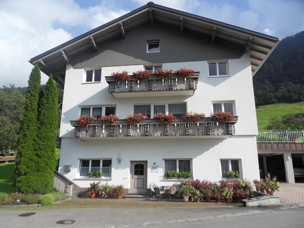 ein weißes Gebäude mit Blumen auf den Balkonen in der Unterkunft Haus Konzett in Dalaas