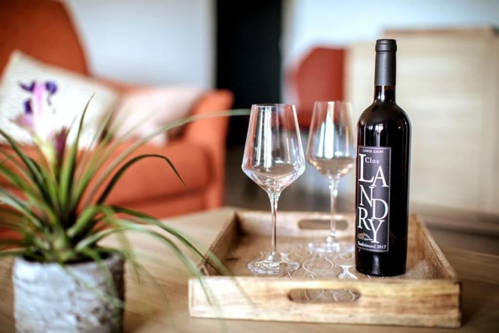 - une bouteille de vin assise sur une table avec 2 verres à vin dans l'établissement T3 Lumineux sans vis à vis à 2 pas du centre..., à Porto-Vecchio
