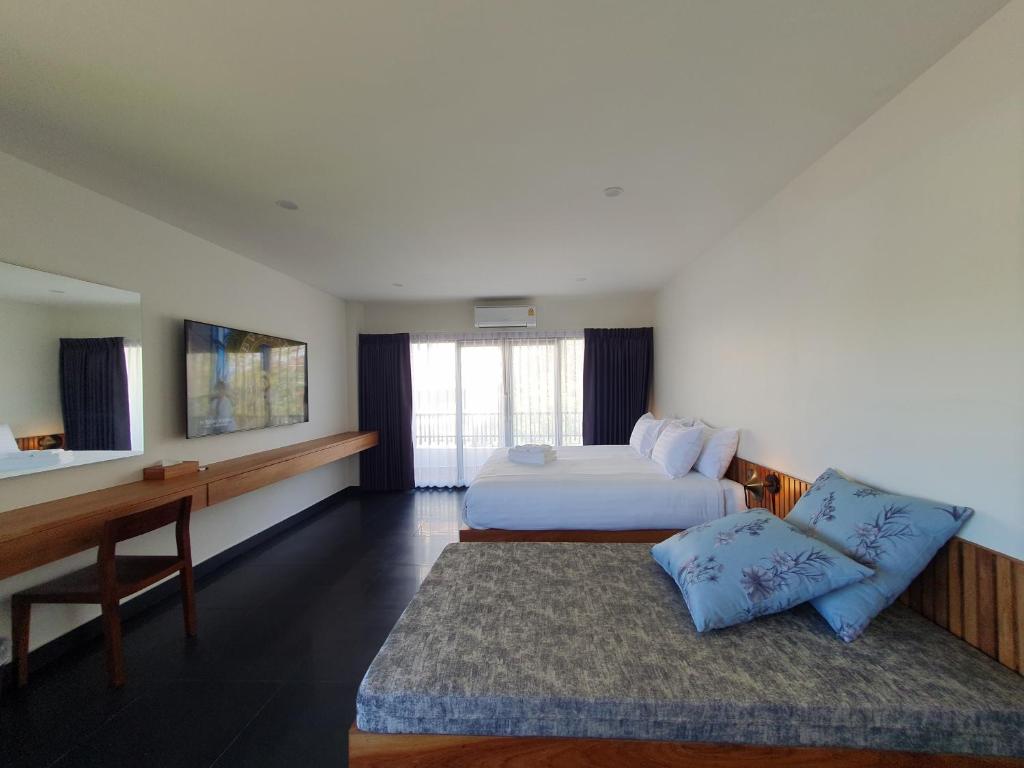 Una habitación de hotel con dos camas y un escritorio. en The Sila Suites - Intrawarorot, en Chiang Mai