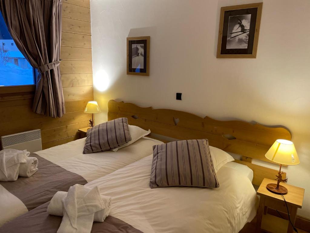 two beds in a room with two lamps and a window at CHALET DES CIMES in Les Menuires