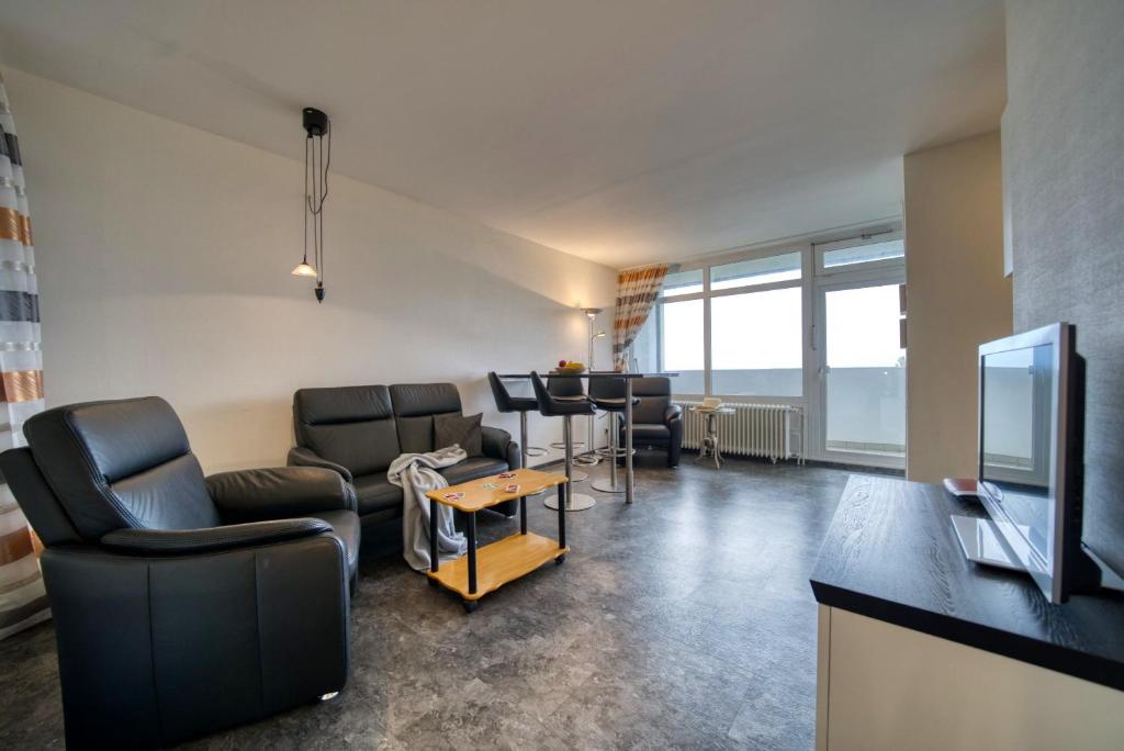 ein Wohnzimmer mit Stühlen, einem TV und einem Tisch in der Unterkunft Ferienpark - Haus B, App 0B0408 in Heiligenhafen