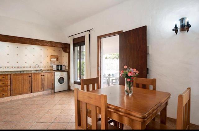 een keuken met een houten tafel en een vaas met bloemen erop bij Villas Pérez Zara 1, 2 y 3 in Conil de la Frontera