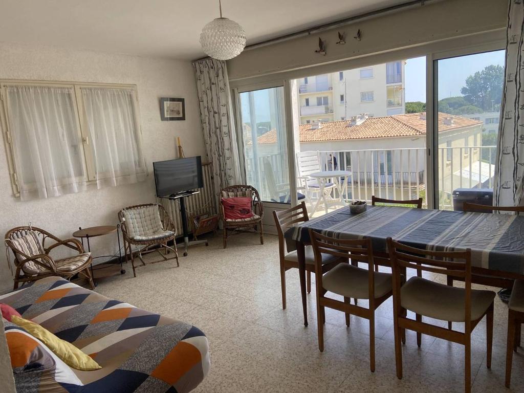 een woonkamer met een tafel en stoelen en een televisie bij BOUCANET Appartement P3 vue sur mer - 2 CHAMBRES POUR 6 PERSONNES - LOGGIA in Le Grau-du-Roi