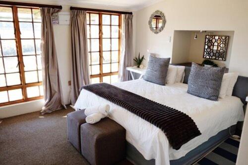 a bedroom with a large white bed with blue pillows at Crane Cottage in Nottingham Road