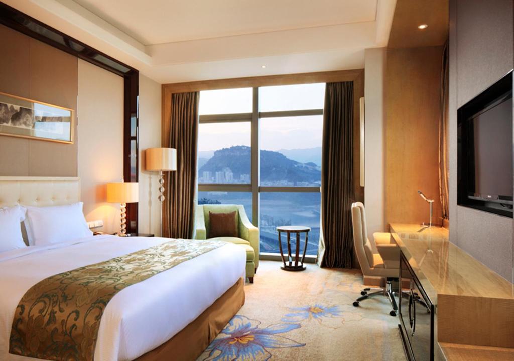 Habitación de hotel con cama, escritorio y ventana grande. en DoubleTree by Hilton Chongqing Wanzhou, en Wanzhou