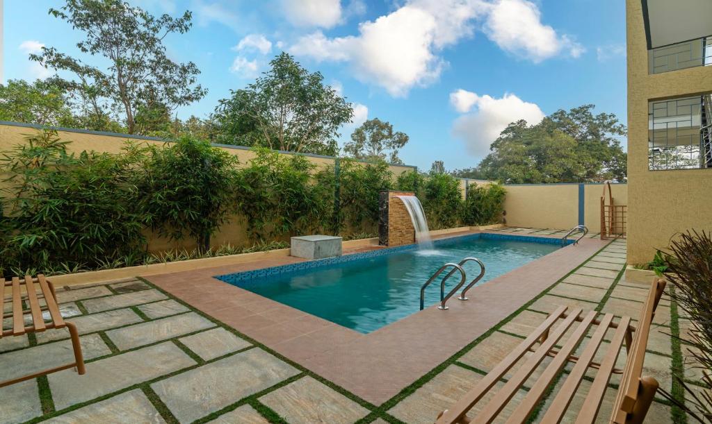 a swimming pool with two chairs next to a building at Itsy By Treebo - Kurinji Stay Inn in Yelagiri