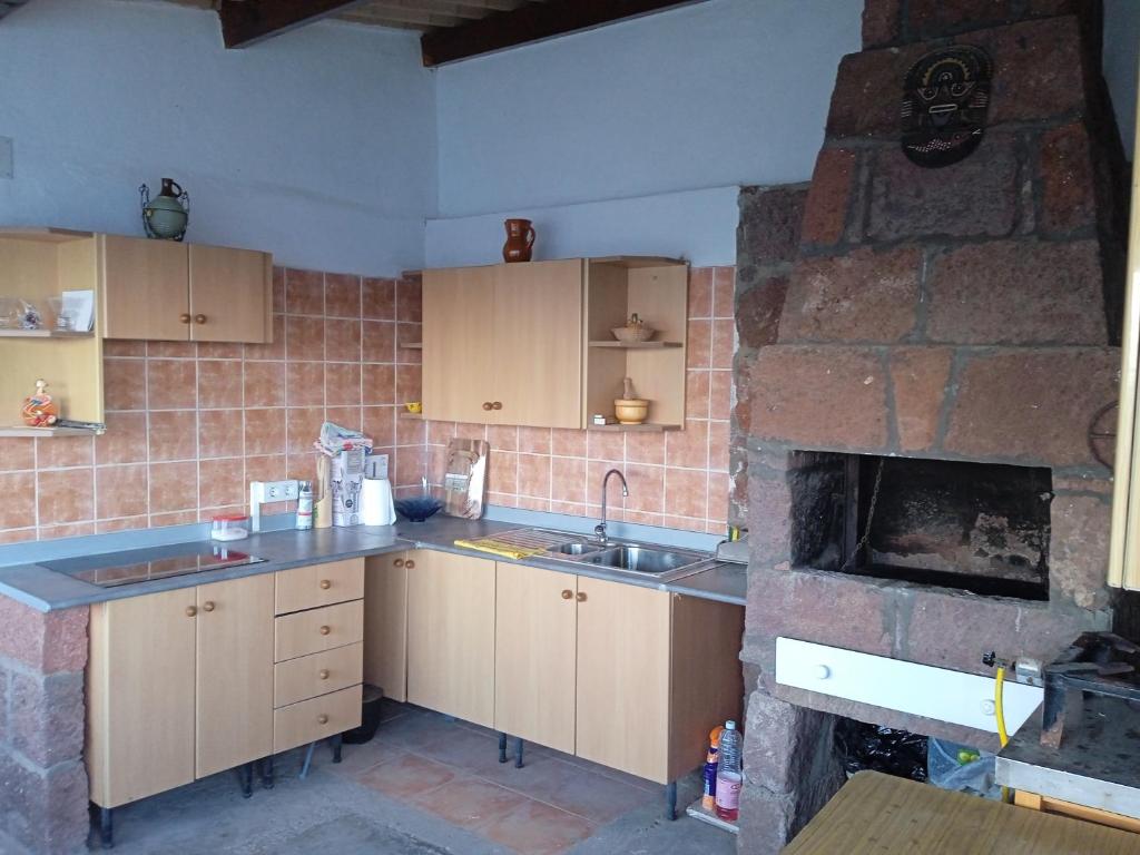cocina con chimenea de ladrillo, fregadero y fogones en Casa lucas, en Almáciga