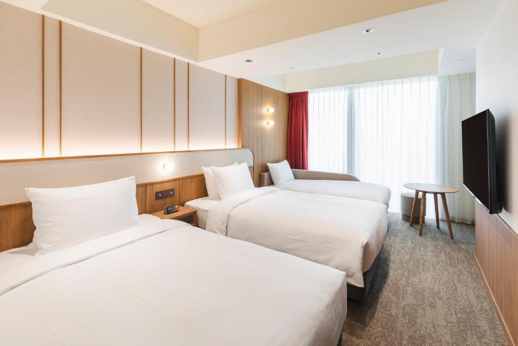 um quarto de hotel com duas camas e uma televisão de ecrã plano em Sotetsu Grand Fresa Taipei Ximen em Taipei