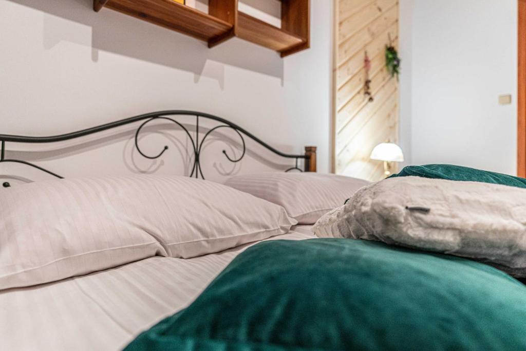 łóżko z białą pościelą i zielonymi poduszkami w obiekcie Aparteo Apartament Brzegi w Zakopanem