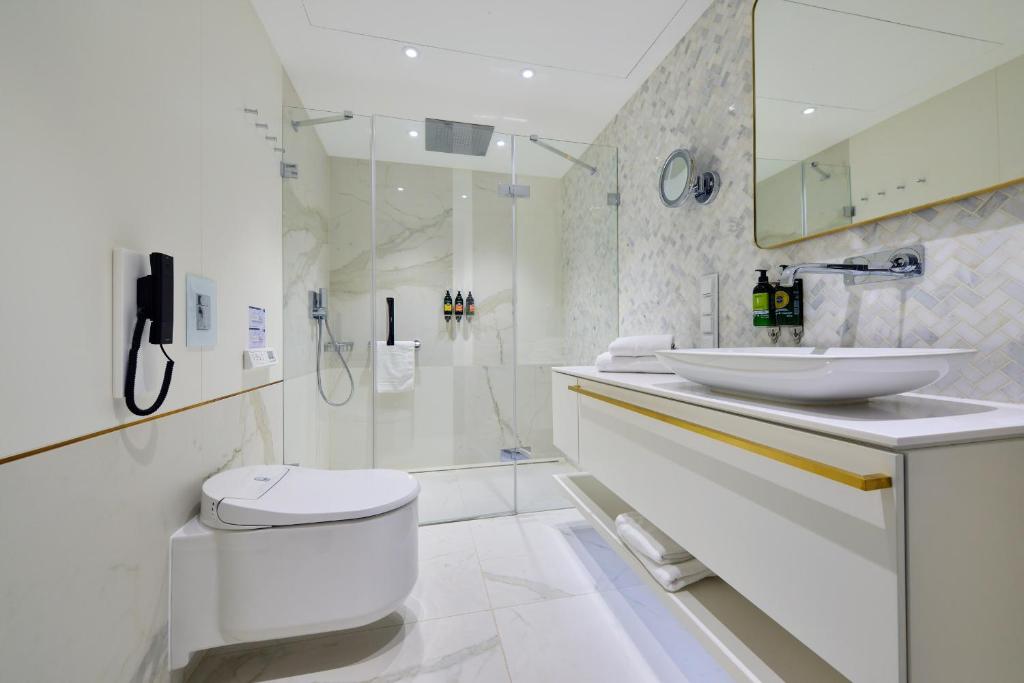 a white bathroom with a toilet and a sink at Hotel Ferreus Modern Art Deco in Krakow