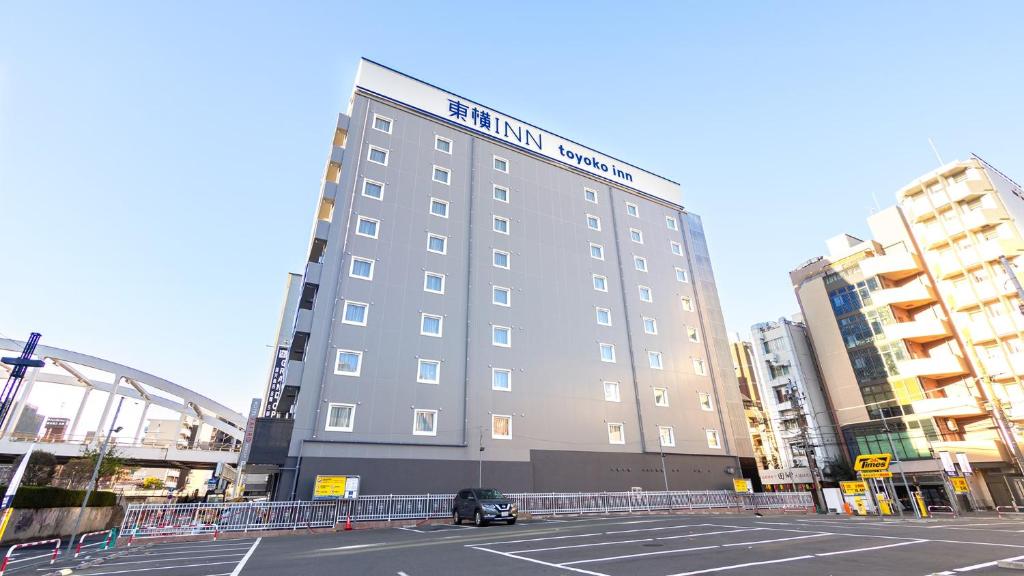 um edifício alto com um carro estacionado em frente em Toyoko Inn Yokohama-eki Nishi-guchi em Yokohama