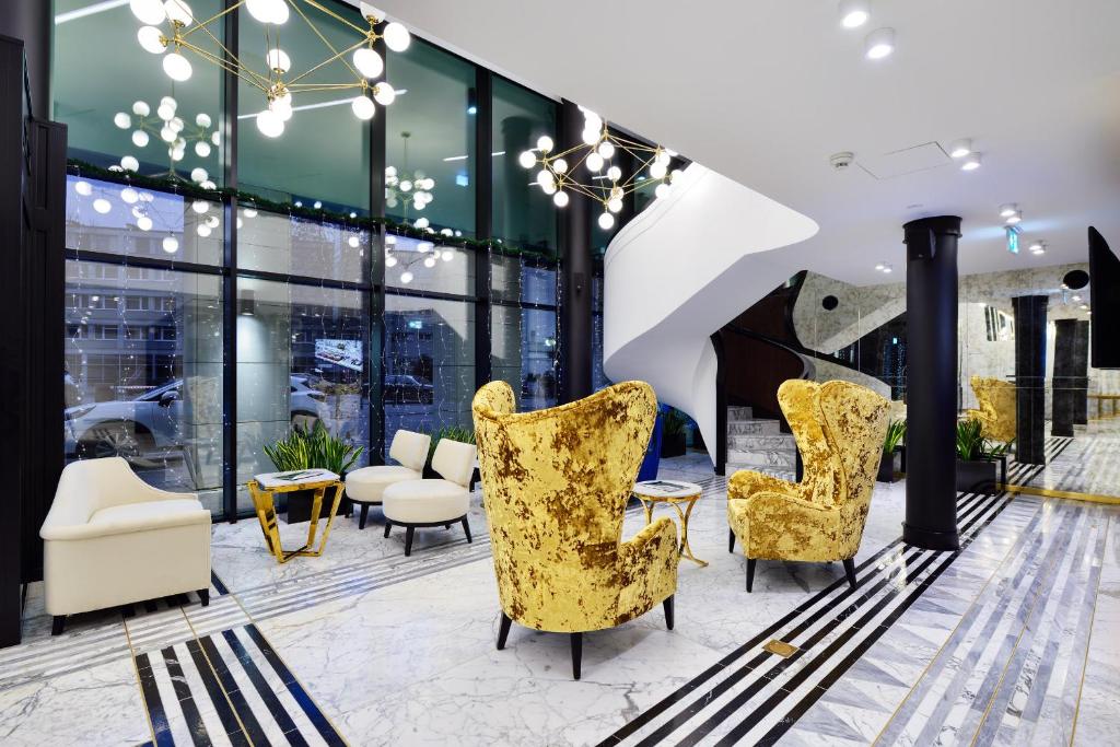 a lobby with yellow chairs and tables and windows at Hotel Ferreus Modern Art Deco in Krakow