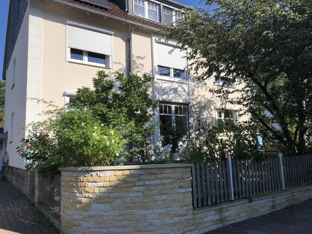 a white house with a brick wall and a fence at Grüne Oase in Bad Nenndorf