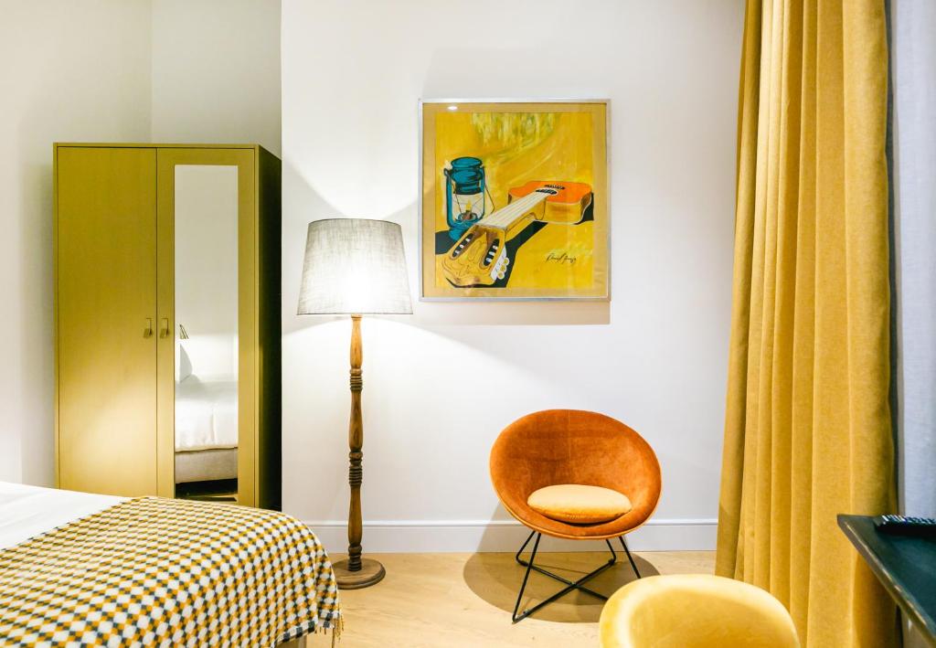 um quarto com uma cama, uma cadeira e um quadro em Joya del Casco Boutique Hotel by Shiadu em Sevilha