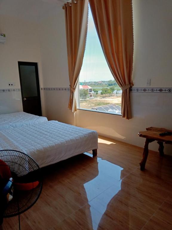 a bedroom with a bed and a large window at Tam Ky XO Hotel in Tam Kỳ