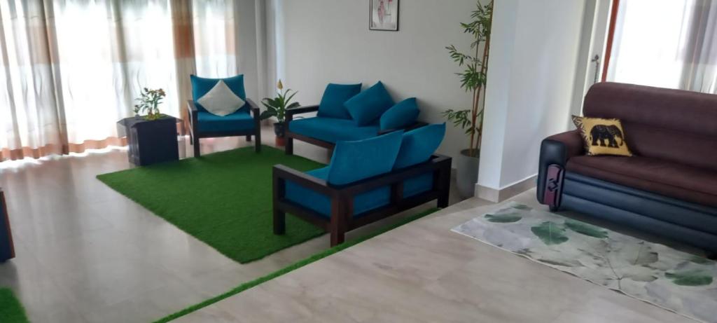 a living room with two blue chairs and a green rug at Hansa Villa in Kandy