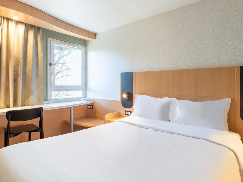 1 dormitorio con cama, escritorio y ventana en B&B HOTEL Lyon Eurexpo Bron, en Bron