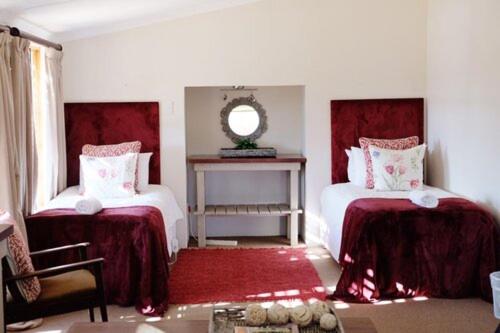 a bedroom with two beds and a mirror on the wall at Ibis Cottage in Nottingham Road