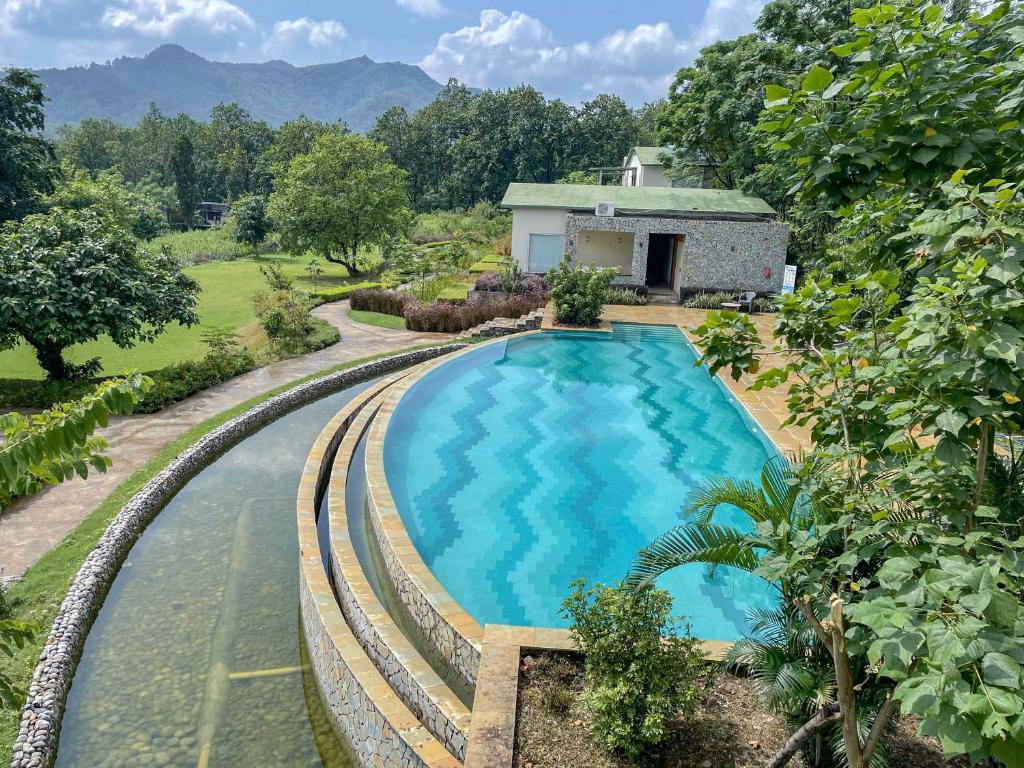 una vista aérea de una piscina frente a una casa en The Corbett Greens en Rāmnagar