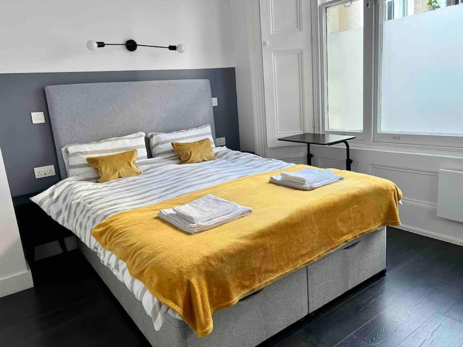 a bedroom with a large bed with a yellow blanket at Small studio in Notting Hill in London