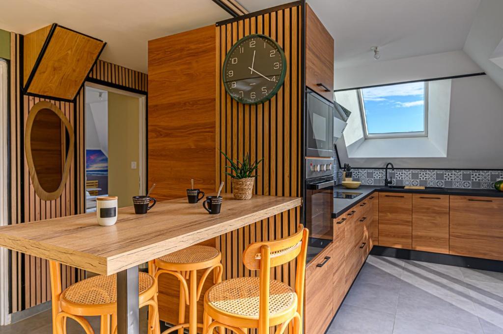 バダンにあるL'Aquagîte - Appt avec terrasse vue merの木製テーブルと壁掛け時計付きのキッチン
