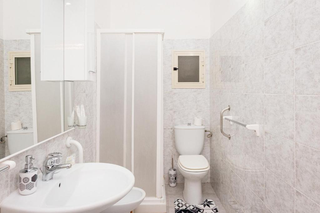 La salle de bains blanche est pourvue de toilettes et d'un lavabo. dans l'établissement Casa Vacanze Petronia-By Faendho, à Porto Torres