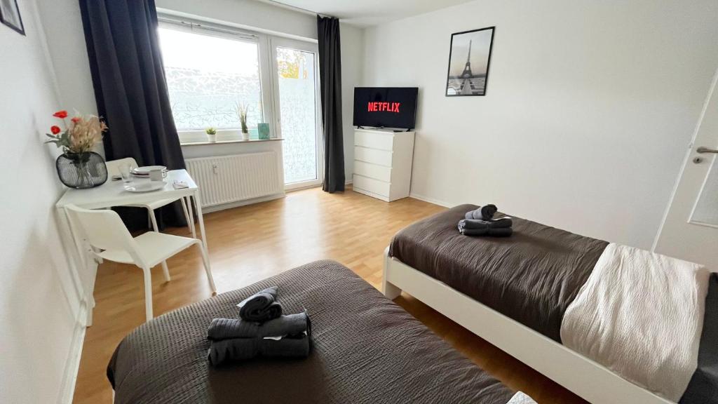 een slaapkamer met 2 bedden en een kleine tafel en een kamer met een tv bij Work & Stay Apartment with Balcony in Osnabrück
