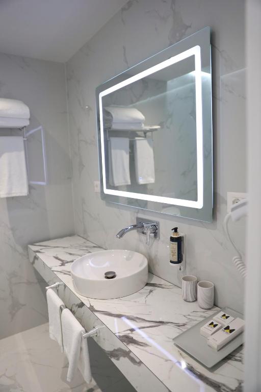 a white bathroom with a sink and a mirror at Metro Hotel Terminal in Tirana