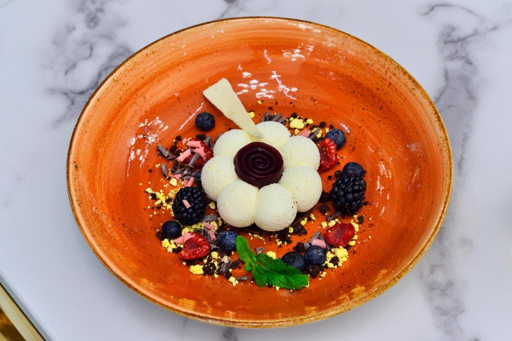a bowl of food with berries and whipped cream at Hotel Ferreus Modern Art Deco in Krakow