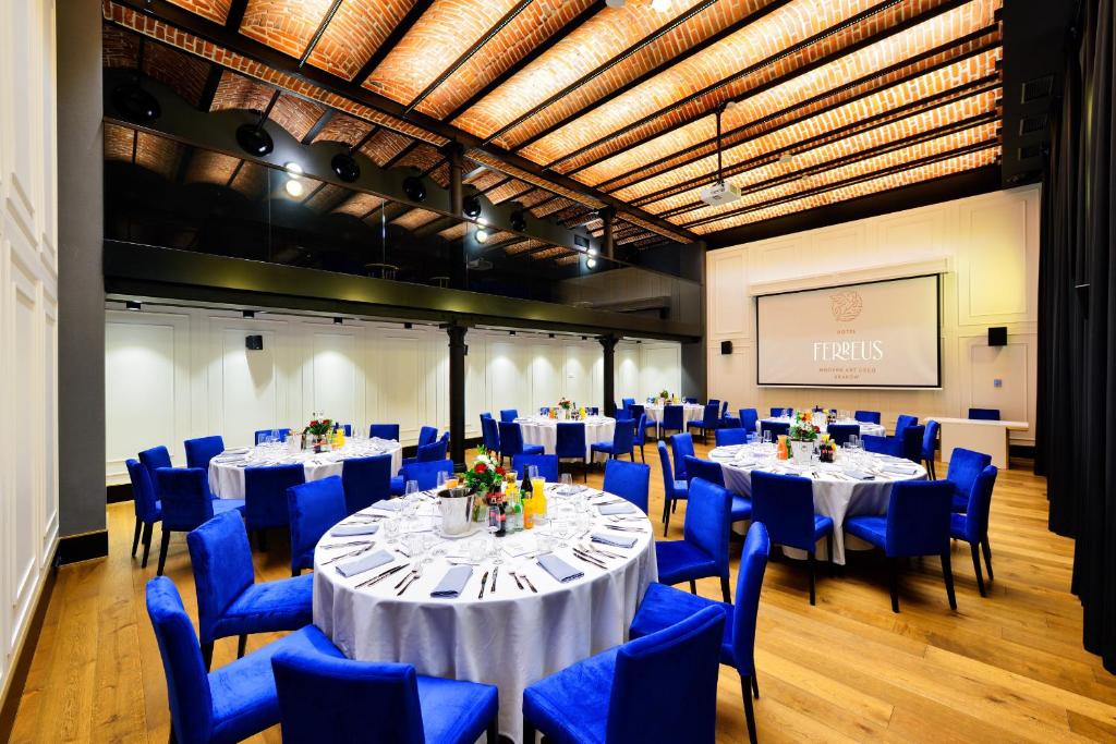 a conference room with tables and blue chairs and a screen at Hotel Ferreus Modern Art Deco in Krakow