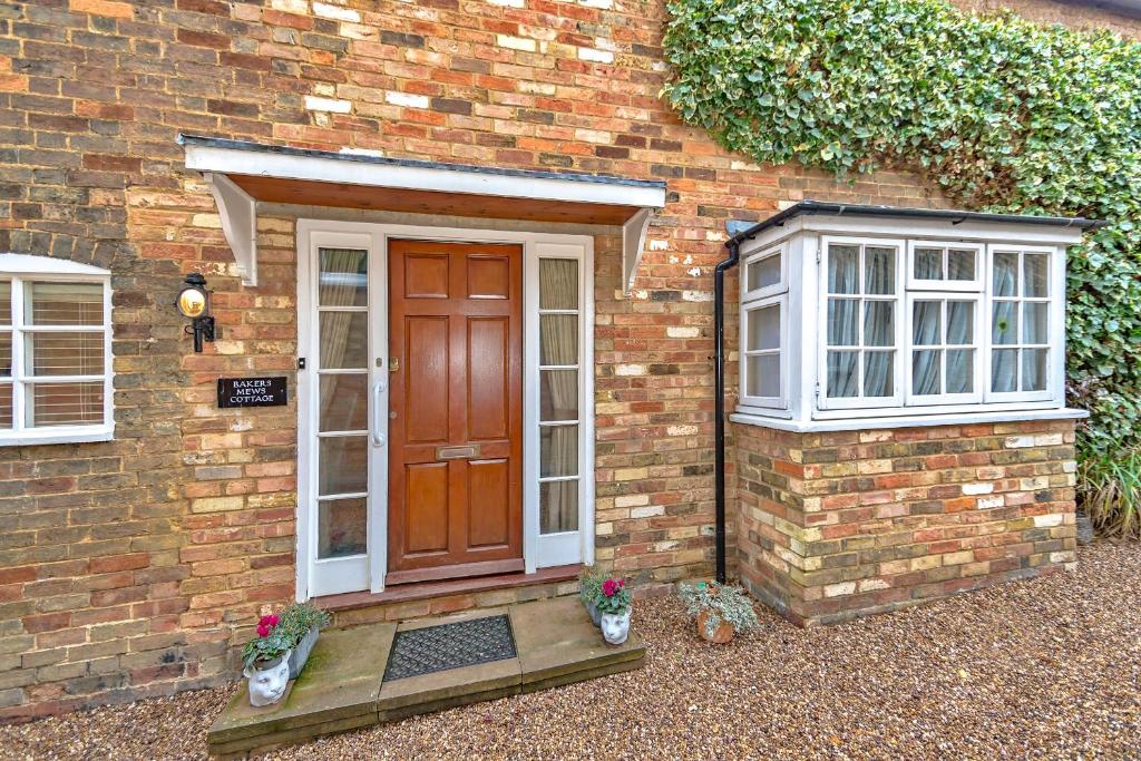 a brick house with a door and two windows at Finest Retreats - Bakers Mews Cottage in Kimbolton